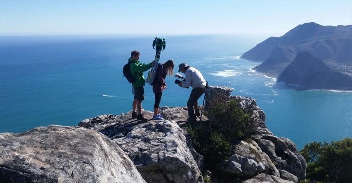 Behind the scenes: #TrekSouthAfrica project lead Andre Van Kets helps Devon Krantz load-up the 22kg Google Trekker backpack as Carte Blanche cameraman Greg Nelson captures the moment with Hout Bay in the background, June 2016. - Photo: Liz Fish