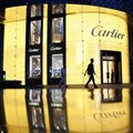 A pedestrian walks past a Cartier store, operated by Richemont, as it stands illuminated at night in Shanghai, China. Picture:
