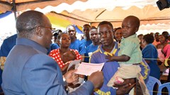 Minister for Constitutional Affairs, Dr Harrison Mwakyembe (L) presents a birth certificate to a parent during the launch of mobile birth registration campaign in Geita and Shinyanga Regions. Tigo Tanzania donated 1,200 mobile phones to support the exercise. Credit: Tigo.