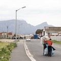 A person takes recyclable material to the drop-off waste site in Retreat visible on the left. Photo: Ashraf Hendricks
