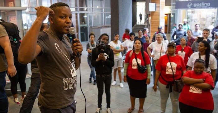 Ndifuna Ukwazi’s Nkosikhona Swartbooi addresses protesters outside the offices of Growthpoint Properties in Claremont. Photo: Ashraf Hendricks