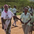 In this 2012 photo, grandmother Janet Kitheka, 63, collects her adopted “granddaughter” Lucy, 13, at the end of the school day in the yard of the Hot Courses Primary School, in the village of Nyumbani which caters to children who lost their parents to HIV, and grandparents who lost their children to HIV in Kenya.