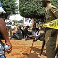 Ugandan journalists sit outside the office of the Daily Monitor, which was closed by armed police. The Monitor's website was recently ordered to suspend publication over a regulatory dispute. (Isaac Kasamani/AFP)