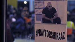 Image via : A woman is reflected next to a poster outside a community hall hosting a night vigil for kidnapped photojournalist Shiraaz Mohamed, on January 18, 2017 in Johannesburg, South Africa. Community members, friends, family and colleagues of photojournalist Shiraaz Mohamed held a night vigil at the Lenasia South Civic Centre. Mohamed was abducted in Syria on 10 January while working with the aid mission Gift of the Givers. (Photo by Gallo Images / Dino Lloyd)