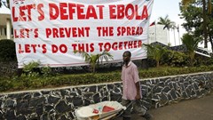 A man pushes a wheelbarrow past a sign in Liberia during the West African Ebola outbreak. AHMED JALLANZO/EPA