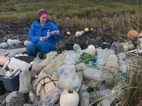Co-author of the study Dr Maëlle Connan with bottles washed ashore on the west coast of Inaccessible Island.