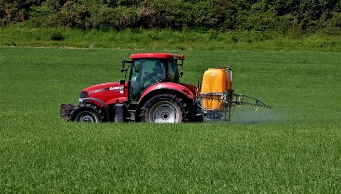 Tractor spraying insecticide on a wheat farm. © Image by  from