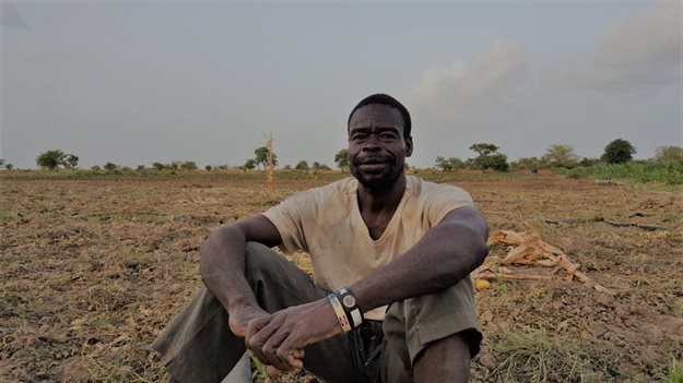 A Ghanaian vegetable farmer sits on his land.