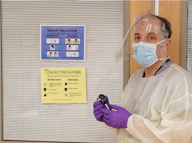 Elazer Edelman, the Edward J. Poitras Professor in Medical Engineering and Science at MIT, wears a face shield developed through a collaborative effort involving groups across MIT while holding an electronic, Bluetooth-enabled stethoscope. In this photo, Edelman is wearing the shield in the snapped up position healthcare workers also have the option to use. Image © Elazer Edelman