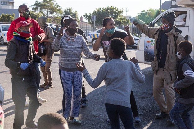 Land occupiers in Observatory, Cape Town, sing struggle songs while law enforcement officers hand out fines to them for contravening by-laws on Wednesday morning. Photo: Ashraf Hendricks / GroundUp