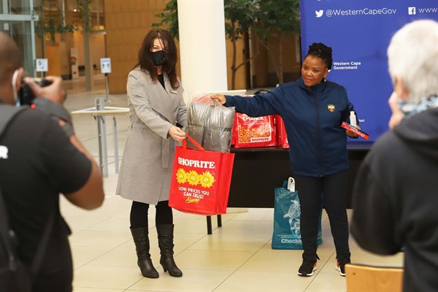 Dr Nomafrench Mbombo, Western Cape MEC for Health, with the contents of the care packs destined for Covid-19 patients in isolation facilities. The Shoprite Group, represented by Wendy van Rensburg (left) donated 250 of these packs which include warm blankets to the Western Cape Department of Health.