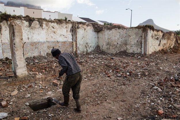 A homeless woman, who has been living on the site, searches for scrap metal among the ruins. Photos by Ashraf Hendricks.