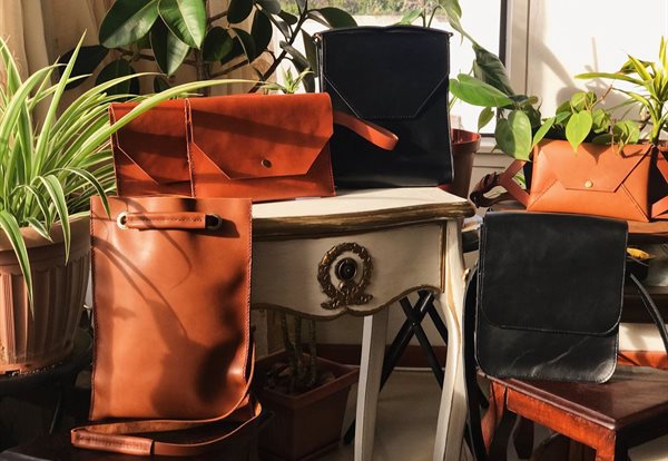 L to R: Sling Tote in Chocolate, Clutch in Tan, Mini Briefcase in Black, Envelope Crossbody in tan and Messenger Bag in Black.