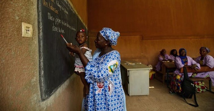 A teacher holds a child as young women learn business skills at Centre D'Apprentissage Feminin (C.A.FE.) in Bamako, Mali, Africa in June 2018. The school is funded by the Canadian NGO Education internationale, a co-operative offering exchange and development services in education. THE CANADIAN PRESS/ Sean Kilpatrick