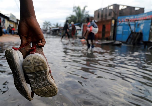 A Congolese man carries his shoes as he wades through floodwaters along a street after the Congo River burst its banks due to heavy rainfall in Kinshasa, Democratic Republic of Congo. Reuters/Kenny Katombe
