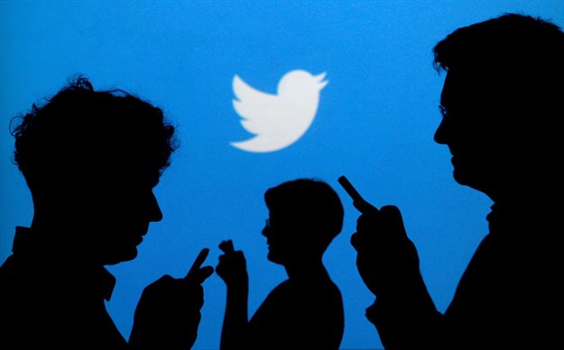 File Photo: People holding mobile phones are silhouetted against a backdrop projected with the Twitter logo in this illustration picture taken September 27, 2013. Reuters/Kacper Pempel/File Photo