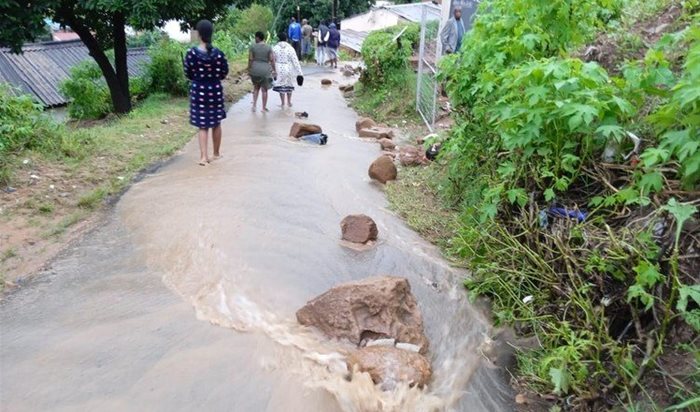 Residents monitor the situation along Mayahe Walk in Ntuzuma H, north of Durban. Stones and sand block the street. | Source: Nokulunga Majola