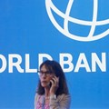 Source: Reuters. A participant stands near a logo of World Bank at the International Monetary Fund - World Bank Annual Meeting 2018 in Indonesia in 2018.