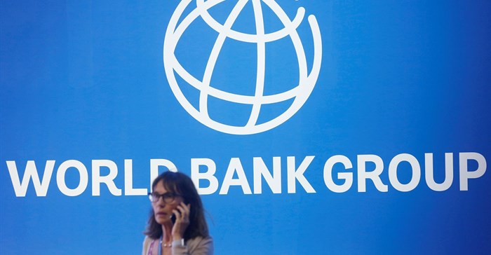 Source: Reuters. A participant stands near a logo of World Bank at the International Monetary Fund - World Bank Annual Meeting 2018 in Indonesia in 2018.