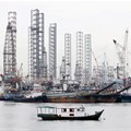 Offshore drilling platforms (rear) stand together at a dock yard near Singapore port. 2015. Source: Reuters/Tim Wimborne