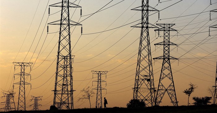 A man walks beneath electricity pylons during frequent power outages caused by its ageing coal-fired plants, in Orlando, Soweto. Source: Reuters/Siphiwe Sibeko