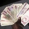 Source: Reuters. A man poses with a handful of Zimbabwean dollars at a bank in central Harare, 15 June 2015. Zimbabweans began exchanging old notes of local dollars for US dollars, as President Robert Mugabe's government sought to officially bury the worthless currency. Reuters/Philimon Bulawayo/File Photo