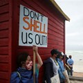A protestor holds a placard as she joins a demonstration against oil major Royal Dutch Shell's plans to start seismic surveys to explore petroleum systems off the country's popular Wild Coast, at Muizenberg beach in Cape Town. Source: Reuters/Mike Hutchings