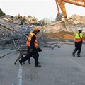 A rescue worker walks with a dog past the site where construction workers are trapped under a building that collapsed in George. Source: Reuters/Esa Alexander