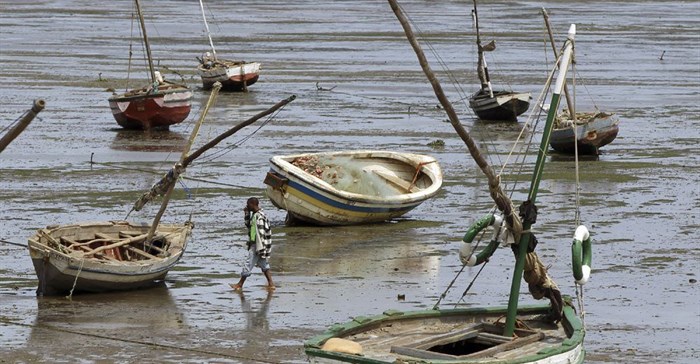 A fisherman walks toward his boat during low tide, in Maputo, 28 September 2010. Reuters/ Goran Tomasevic/File Photo