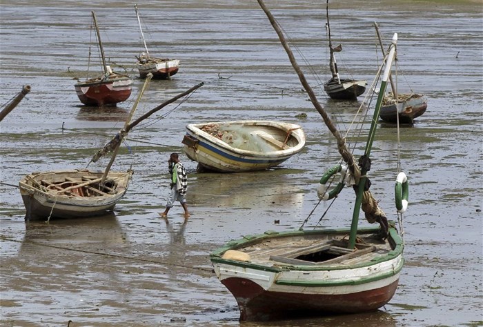 A fisherman walks toward his boat during low tide, in Maputo, 28 September 2010. Reuters/ Goran Tomasevic/File Photo