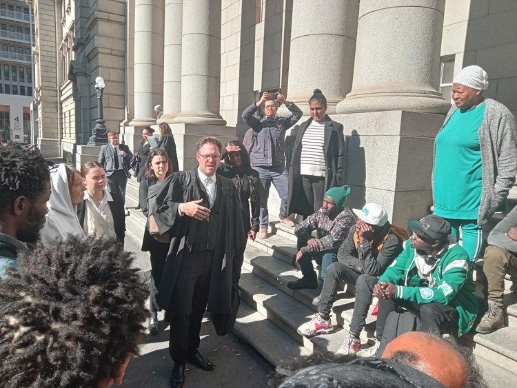 Outside the Western Cape High Court, Ndifuna Ukwazi attorney Jonty Cogger speaks to applicants urgently seeking an interdict preventing PRASA from evicting them from land they have occupied for years. Photo: Sandiso Phaliso / GroundUp