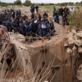 Community members watch as Senzo Mchunu, South African police minister, inspects outside the mineshaft where it is estimated that hundreds of illegal miners are believed to be hiding underground, after police cut off food and water as part of police operations against illegal miners, in Stilfontein. Source: Reuters/Ihsaan Haffejee