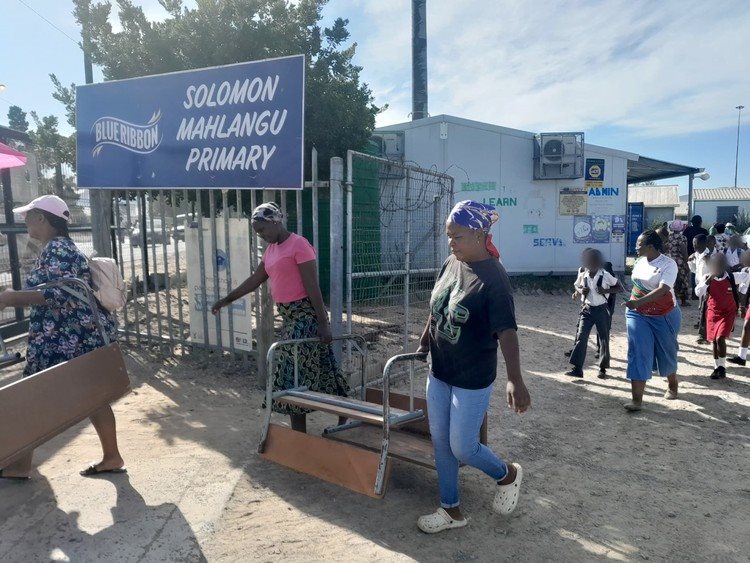 Parents carry out school desks from Solomon Mahlangu Primary. They want their children to be transferred to Blue Ridge Primary School.