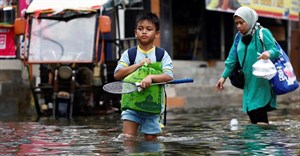 People walk through water at a flooded area affected by rising sea levels and land subsidence in North Jakarta, Indonesia, 20 November 2024. Reuters/Willy Kurniawan/File Photo