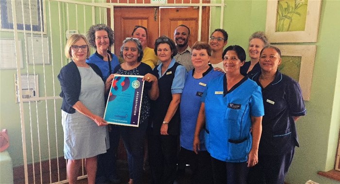 Front left: Jacqui Stewart, CEO of Cohsasa, presents the newly branded accreditation certificate to operational manager, Justine Goliath, as proud members of staff accreditation team look on. | From left (front): Sr Elmarie van Dyk, Staff Nurse Sonja Nel, Magdalene Galant (home-based carer) | From left (back) Sr Marietha Nel, Corne Coetzee (financial manager), Sr Lesley Philander, Renicia Moses (office administrator), Sr Susan Swanepoel (IDT manager) and Sally Appollis (social auxiliary worker)