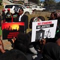Protesters hold placards as lead applicant and lawyer Mzwandile Masuku addresses them outside the court, after a hearing was postponed, in Mbabane, Eswatini, 22 August 2025. Reuters/Zakhele Mabuza