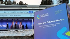 People walk next to a Standard Chartered banner, on the first day of the annual meeting in Davos, Switzerland, 15 January 2024. Reuters/Denis Balibouse/File Photo