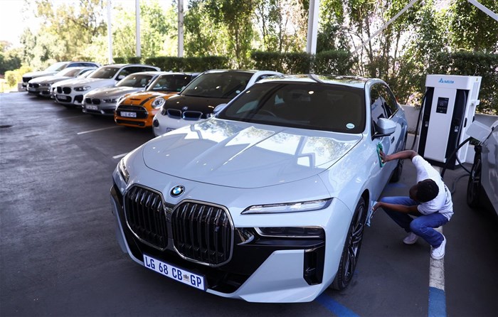 A worker cleans a BMW i7 xDrive60 elecric car while it is charging at a BMW dealership in Sandton, South Africa, on 27 October 2023. Reuters/Siphiwe Sibeko