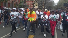 CWP worker Ewart Sithebe, in the yellow jacket with a microphone, led the crowd. Photo: Warren Mabona / GroundUp