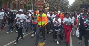 CWP worker Ewart Sithebe, in the yellow jacket with a microphone, led the crowd. Photo: Warren Mabona / GroundUp