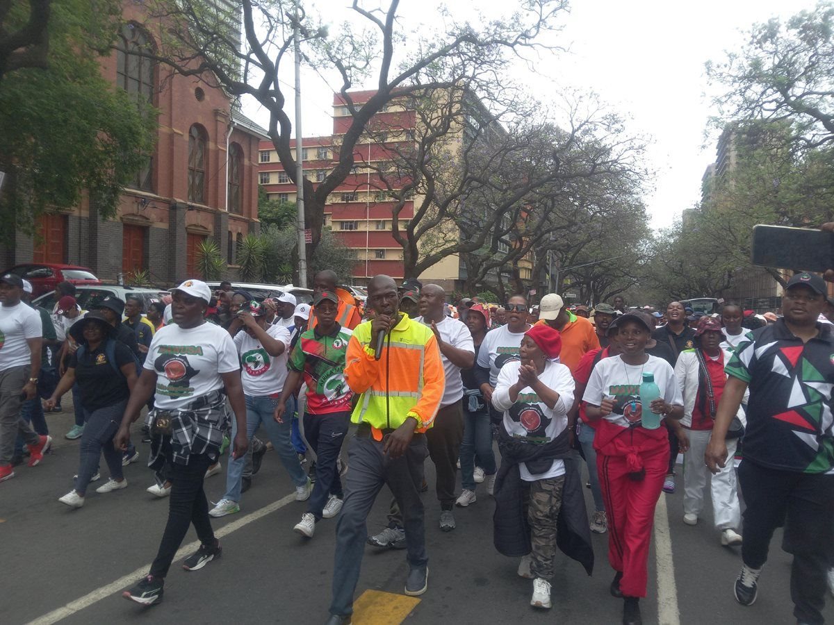 CWP worker Ewart Sithebe, in the yellow jacket with a microphone, led the crowd. Photo: Warren Mabona / GroundUp
