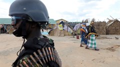 Women walk past a Mozambique soldier inside a camp for the internally displaced in the town of Quitunda, Mozambique, 22 September 2021. Image credit: Reuters/Baz Ratner/File Photo