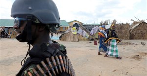 Women walk past a Mozambique soldier inside a camp for the internally displaced in the town of Quitunda, Mozambique, 22 September 2021. Image credit: Reuters/Baz Ratner/File Photo