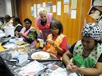 Mama Mary of Winterveld looks on while Prof Elain evaluates Mama Jacqueline of Tesselaarsdal’s work and Mama Emily of Muldersdrift is very focussed on her mosaic.
